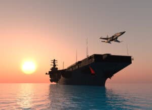 1. Military aircraft flying over an aircraft carrier at sunset, showcasing naval aviation and defense technology.