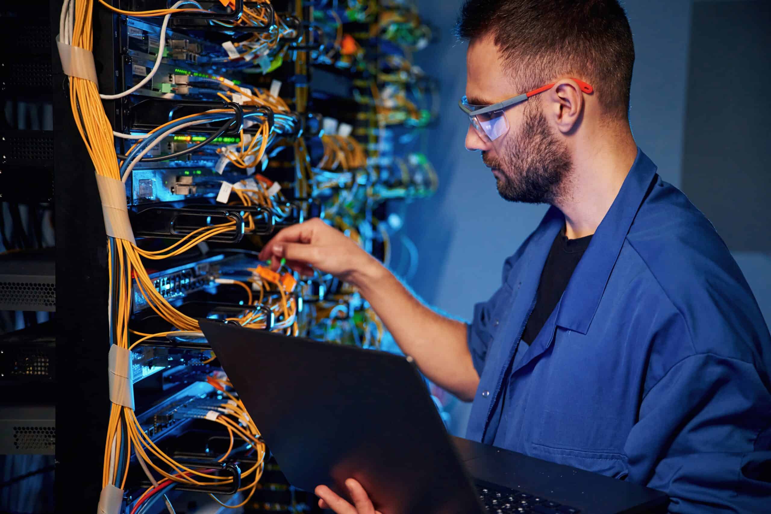High-tech network technician working on server rack with colorful cables, ensuring optimal data and network security, highlighting technical expertise in data management and infrastructure.