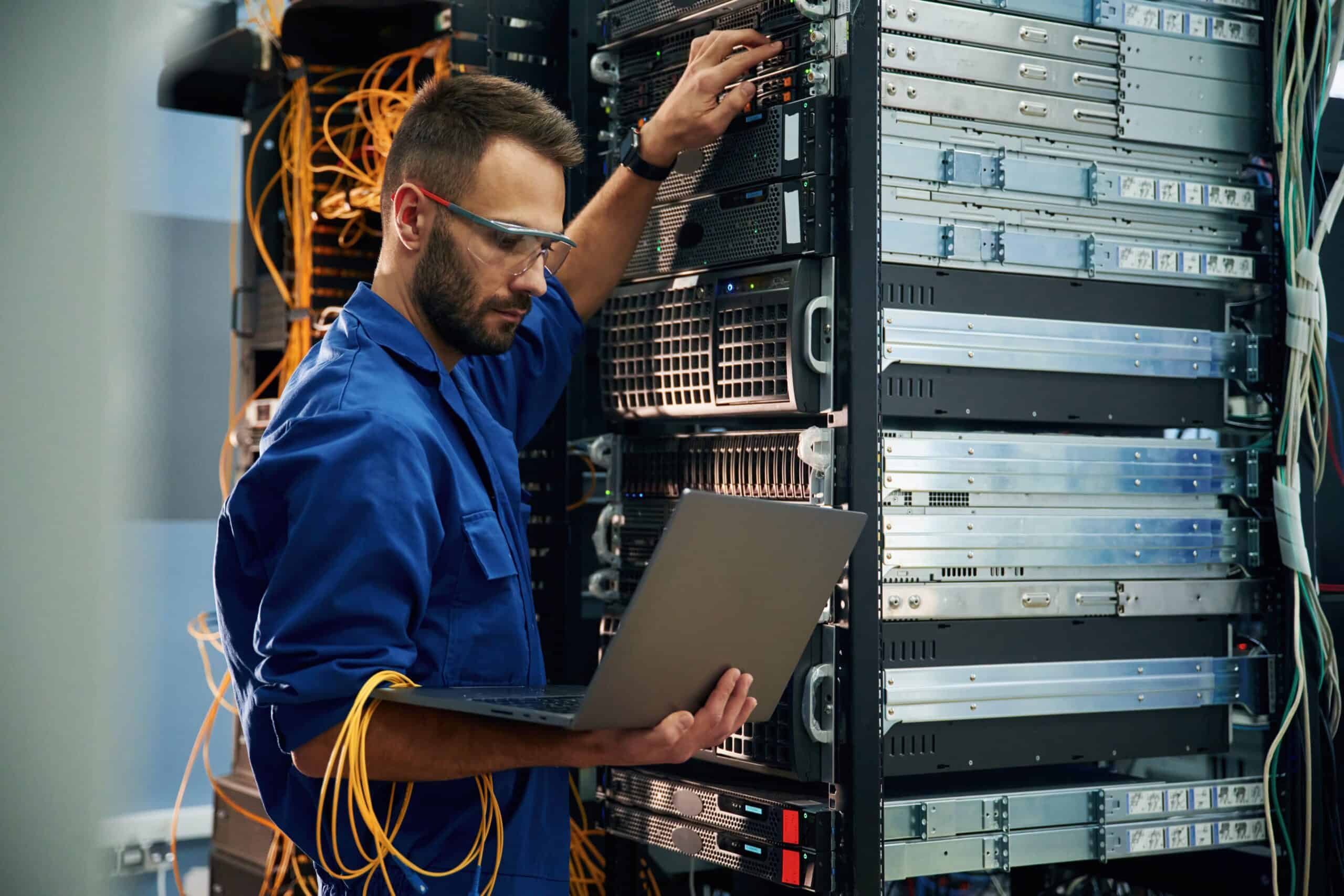 High-tech IT technician working on server rack in data center, performing hardware maintenance and diagnostics, ensuring optimal performance of enterprise IT infrastructure.
