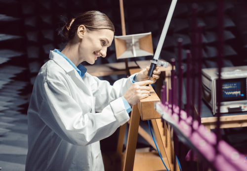 High-quality researcher smiling while working on an electronic device in laboratory environment.
