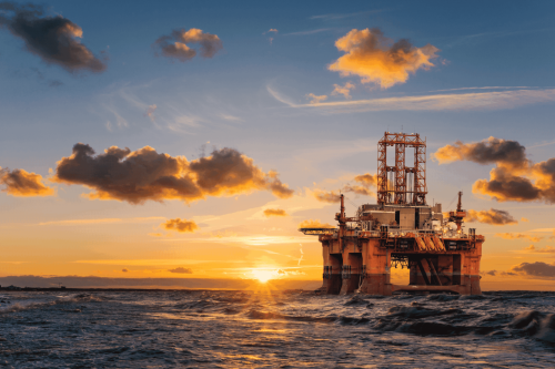 Offshore oil rig during sunset with dramatic clouds and ocean waves, showcasing energy infrastructure in marine environment, ideal for oil and energy industry visuals.