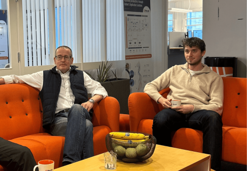 A professional setting showcasing collaborative work environment with orange seating, technology, and branding for Recab, a digital solutions provider.